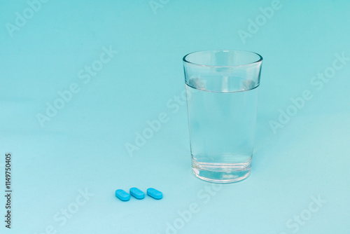 Billede på lærred A glass of water with blue pills on blue background