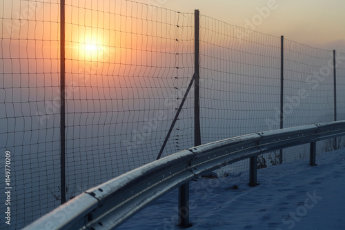 Obraz na płótnie Sunset in a city where the air is so polluted that you can barely see anything. View from a road fenced with steel mesh. w salonie