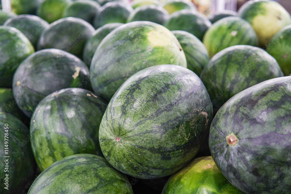 A pile of whole fresh watermelons displayed in a fruit shop is suitable for design purposes, as an illustration for articles about fruits and others. A pile of whole fresh watermelons displayed in a fruit shop is suitable for design purposes, as an illustration for articles about fruits and others.