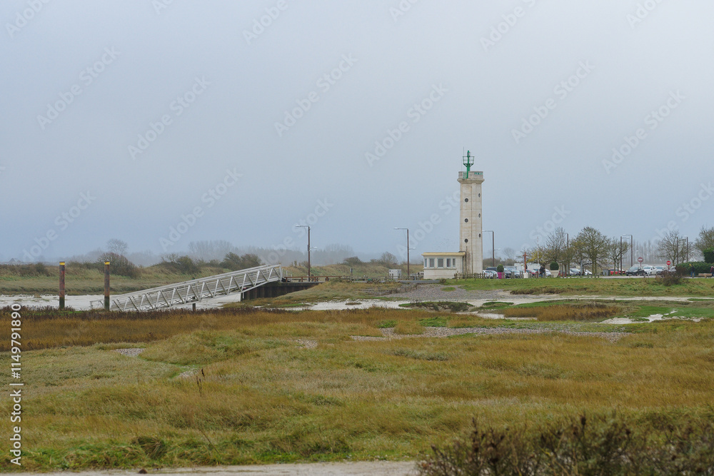 Lighthouse standing tall by the shore on a cloudy day with a wooden pier in the foreground Lighthouse standing tall by the shore on a cloudy day with a wooden pier in the foreground
