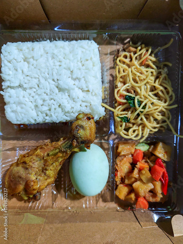 In Indonesian it is called Rice Box or Nasi kotak with side dishes of fried noodles, fried chicken, eggs, and vegetables. Usually distributed during celebrations or catering packaging. photo