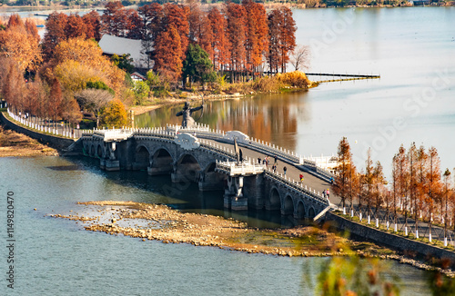 Arched Bridge with Archer Statue in Autumn Landscape photo