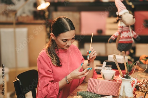 Engaged in the delightful art of making Christmas ornaments, a woman brings holiday spirit to life surrounded by warm decorations and festive crafts photo