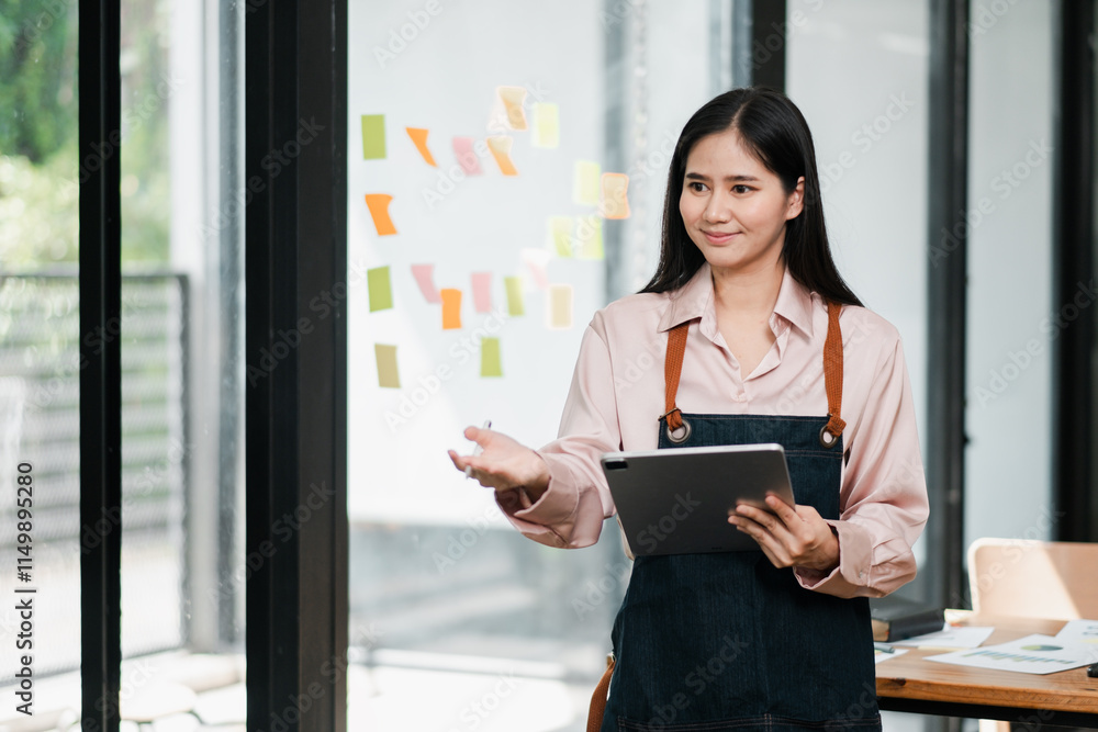 Young woman in casual attire presenting in a modern office setting, using a tablet and sticky notes on a glass wall. Young woman in casual attire presenting in a modern office setting, using a tablet and sticky notes on a glass wall.