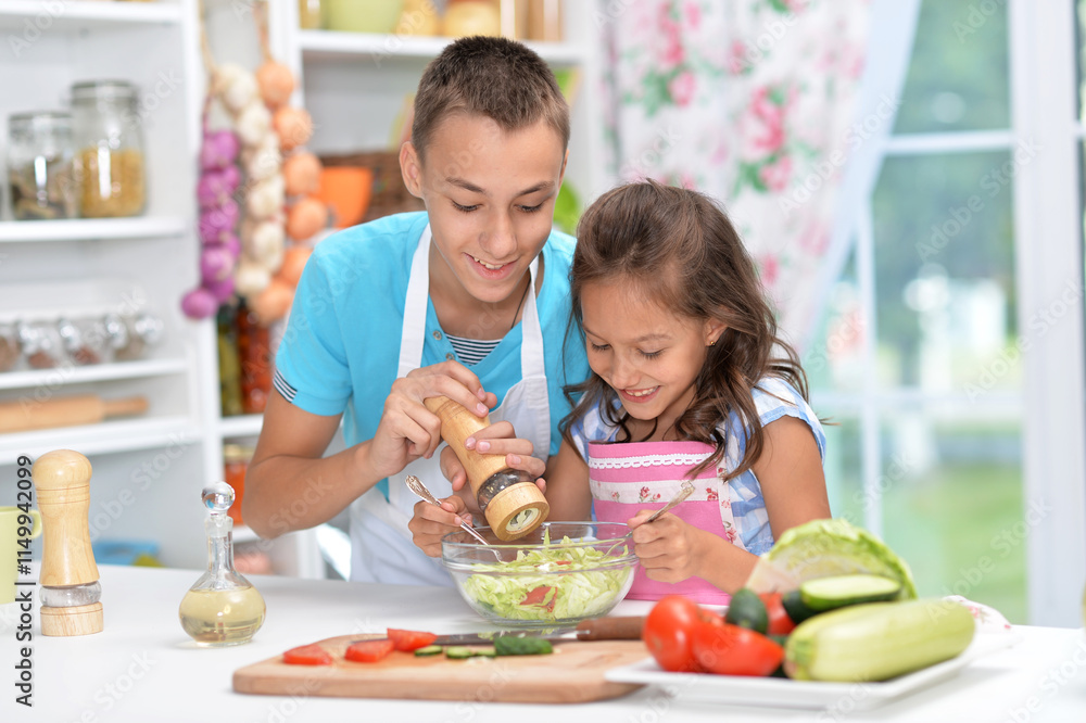 Cute little brother and sister preparing salad together at kitchen Cute little brother and sister preparing salad together at kitchen
