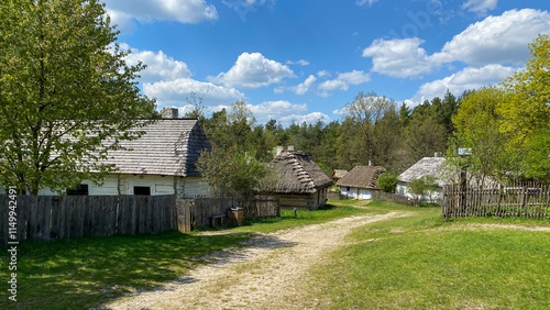 Polish old wooden countryside with sandy path during summer time with blue light cloudy sky
