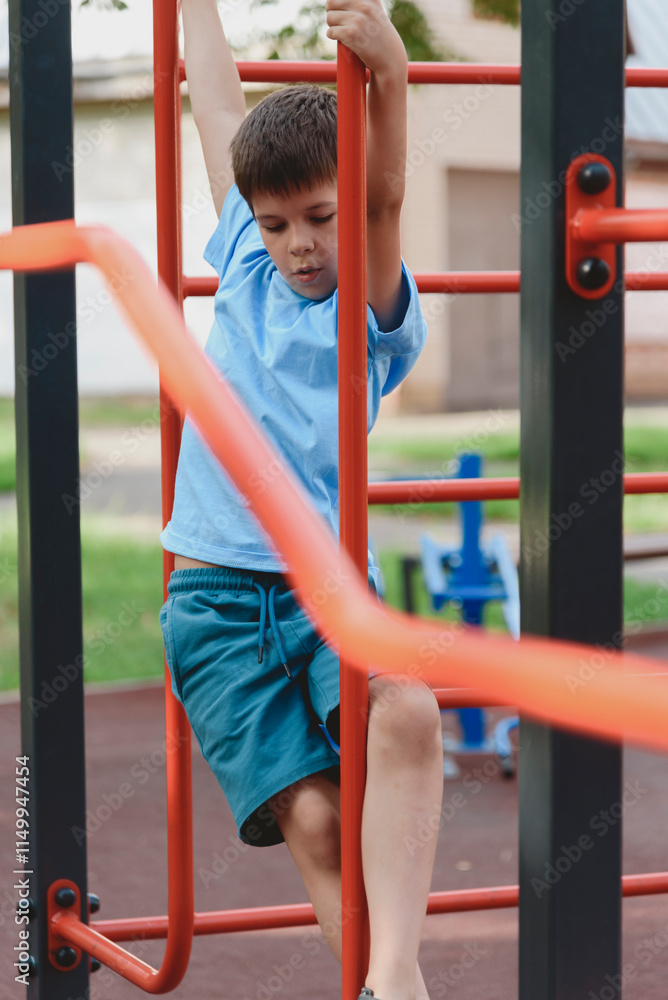 Obraz premium Happy boy playing and hanging on steel bar on playground. Children's exercises for health and concentration.