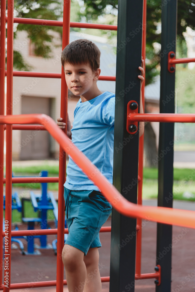 Obraz premium Happy boy playing and hanging on steel bar on playground. Children's exercises for health and concentration.