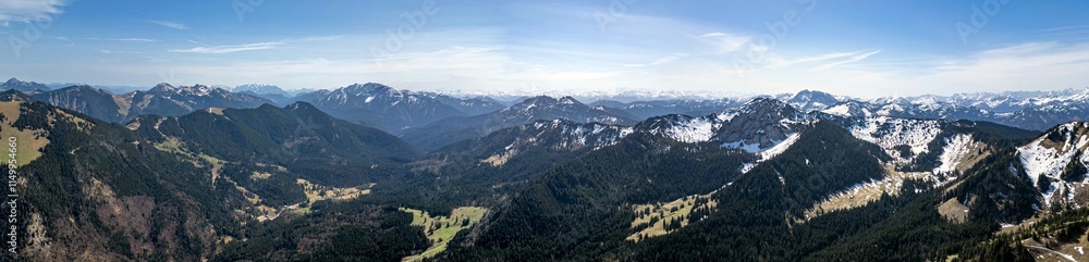 Panoramic aerial view of the foothills of the Alps in Bavaria. Edge of mountains, sky and clouds. The mountains are covered with snow and forests. Panoramic aerial view of the foothills of the Alps in Bavaria. Edge of mountains, sky and clouds. The mountains are covered with snow and forests.
