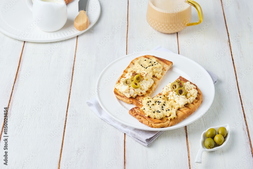 Healthy breakfast, two open sandwiches with hummus, egg salad and olives on white plate on light wooden background. Healthy food. Healthy breakfast, two open sandwiches with hummus, egg salad and olives on white plate on light wooden background. Healthy food.