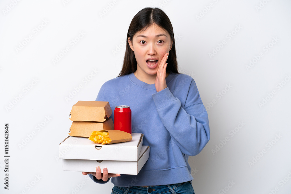 Young Chinese woman holding fast food isolated on white background with surprise and shocked facial expression Young Chinese woman holding fast food isolated on white background with surprise and shocked facial expression