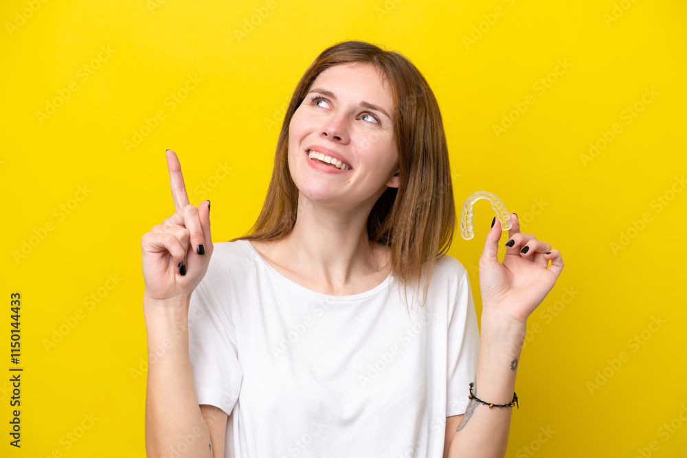 Young English woman holding invisible braces pointing up a great idea Young English woman holding invisible braces pointing up a great idea