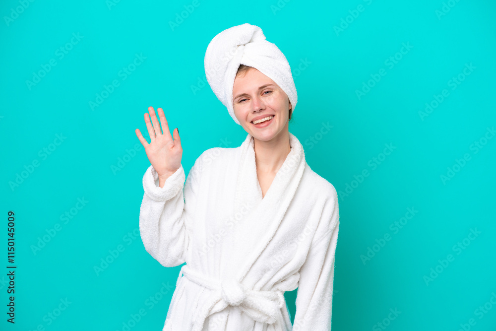 Young woman in a bathrobe isolated on blue background saluting with hand with happy expression Young woman in a bathrobe isolated on blue background saluting with hand with happy expression