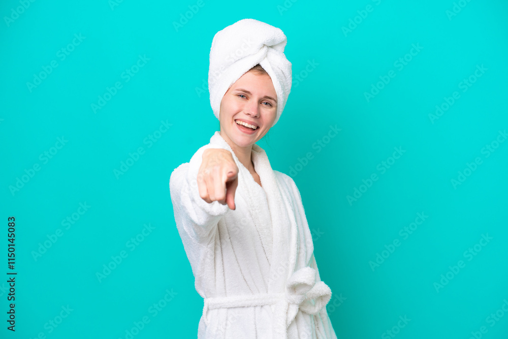 Young woman in a bathrobe isolated on blue background points finger at you with a confident expression Young woman in a bathrobe isolated on blue background points finger at you with a confident expression