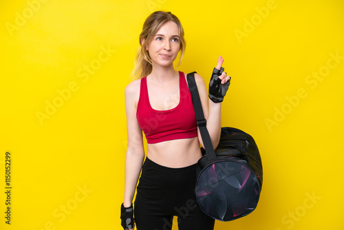 Young sport caucasian woman with sport bag isolated background with fingers crossing and wishing the best photo