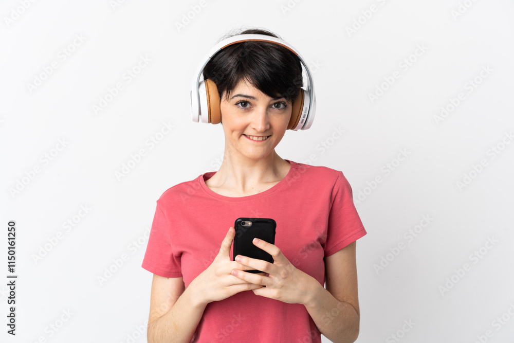 Woman with short hair isolated on white background listening music with a mobile and looking front Woman with short hair isolated on white background listening music with a mobile and looking front