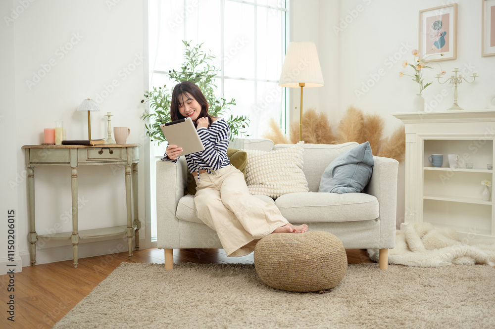 Young Woman Enjoying Leisure Time Reading on a Tablet in a Cozy Living Room Young Woman Enjoying Leisure Time Reading on a Tablet in a Cozy Living Room