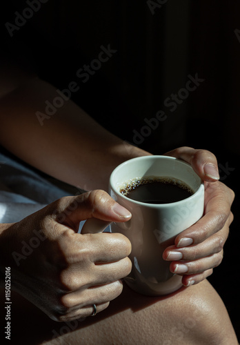 Obraz na płótnie Close-up of Comforting cozy female hands holding a coffee mug with the morning sunlight that shines through. Dark tone, use it as your Wallpaper, Poster and Copy space, Selective focus. w salonie