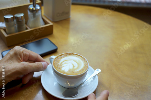 Human's hand holding coffee cup on table.