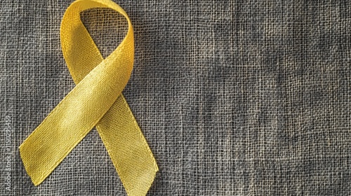 Yellow ribbon on textile background with copy space for endometriosis awareness month or sign for microencephaly and suicide prevention photo