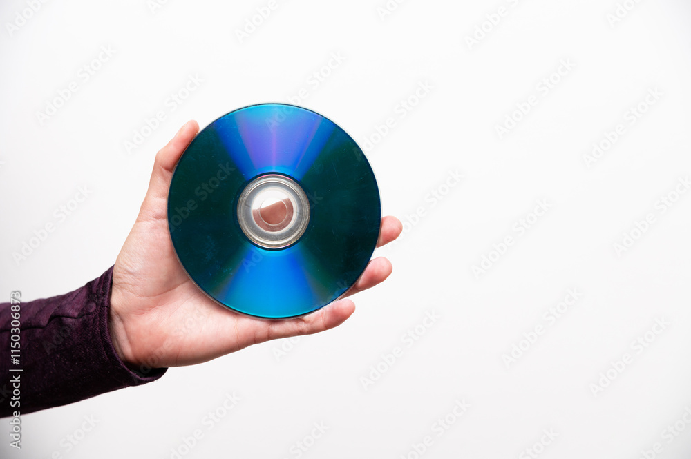 Compact disc in a woman's hand, rainbow side up, glittering on a white wall background Compact disc in a woman's hand, rainbow side up, glittering on a white wall background