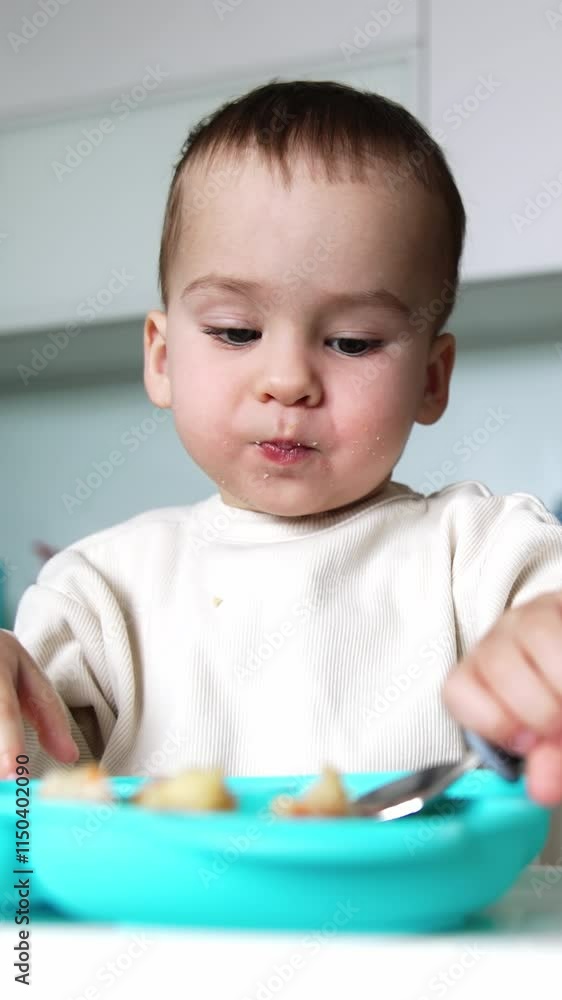 Little kid eating from plate using spoon. Baby is growing , developing and learning. Vertical video Little kid eating from plate using spoon. Baby is growing , developing and learning. Vertical video