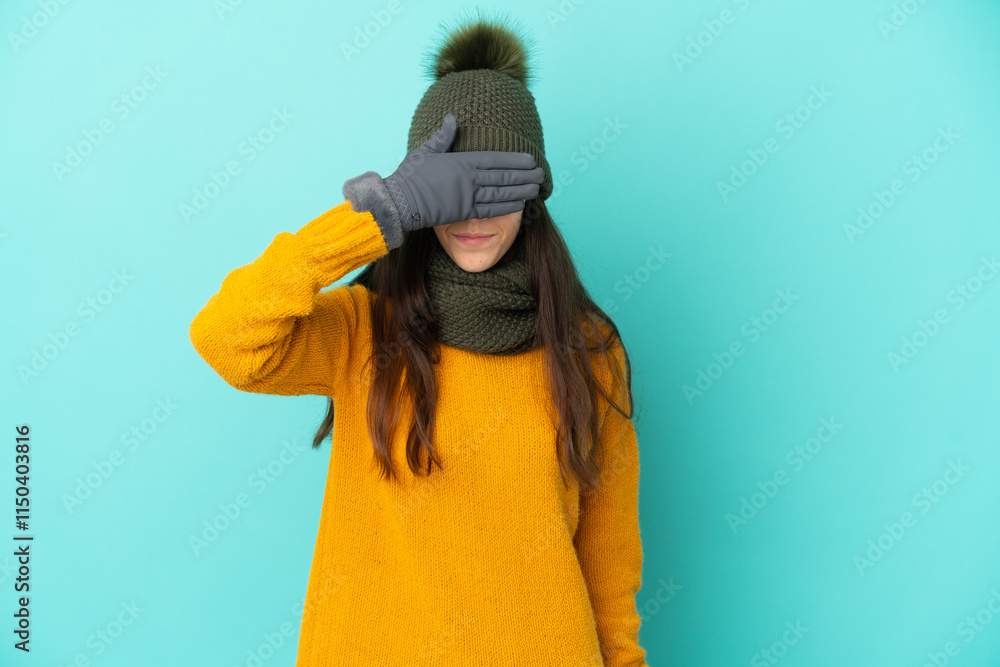 Young French girl isolated on blue background with winter hat covering eyes by hands. Do not want to see something Young French girl isolated on blue background with winter hat covering eyes by hands. Do not want to see something