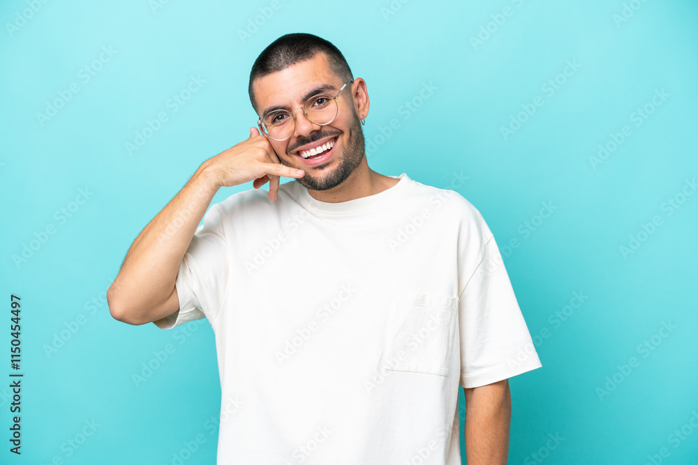 Young caucasian man isolated on blue background making phone gesture. Call me back sign Young caucasian man isolated on blue background making phone gesture. Call me back sign