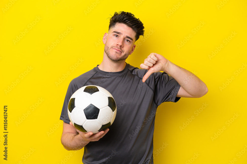 Handsome young football player man isolated on yellow background showing thumb down with negative expression Handsome young football player man isolated on yellow background showing thumb down with negative expression