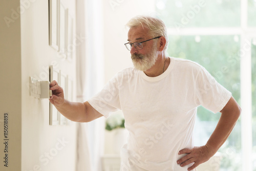 Fotografia Man adjusting thermostat. Home temperature.