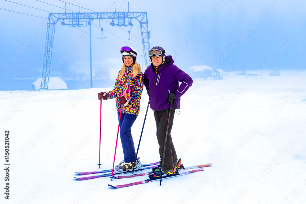 Two father and daughter skiers enjoying a beautiful day on the slopes surrounded by nature and snow