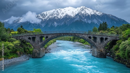 Wallpaper Mural Majestic stone arch bridge spans a turquoise river, nestled beneath snowy mountain peaks. Lush greenery surrounds the scene. Torontodigital.ca