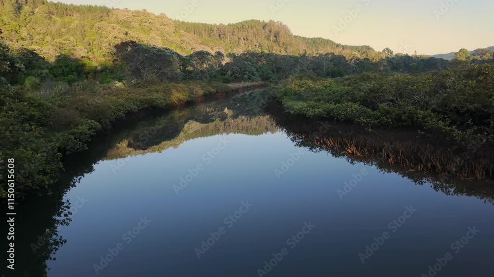 Tranquil coastal scene at dawn. Calm waters reflect the hills and trees. No people are present. OPOUTERE, WHANGAMATA, COROMANDEL PENINSULA, NEW ZEALAND Tranquil coastal scene at dawn. Calm waters reflect the hills and trees. No people are present. OPOUTERE, WHANGAMATA, COROMANDEL PENINSULA, NEW ZEALAND