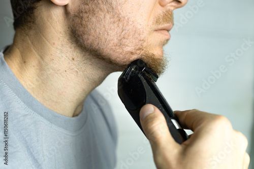 A man trims his beard with a trimmer. Close up. An electric razor trimming a beard. Beard care at home. photo