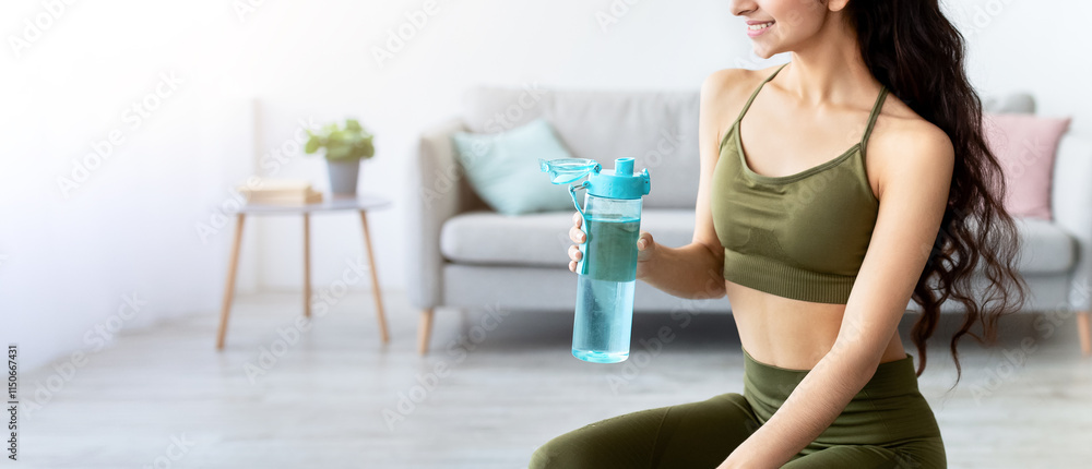 Charming Indian lady in sportswear sitting on fitness ball with bottle of clear water at home. Attractive Asian woman keeping hydrated during domestic training, working out indoors Charming Indian lady in sportswear sitting on fitness ball with bottle of clear water at home. Attractive Asian woman keeping hydrated during domestic training, working out indoors