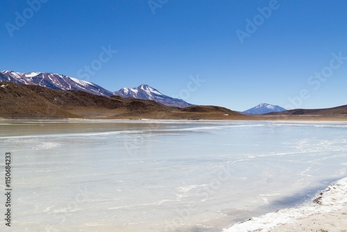 Frozen lake and snow-capped mountains under blue sky