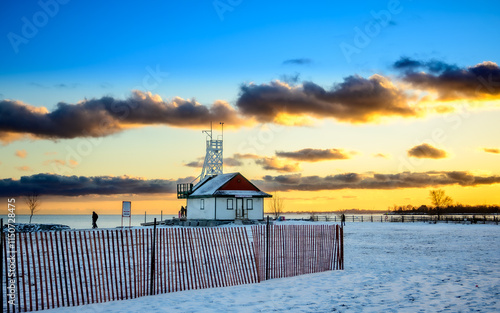 Photography Sunset on Kew Beach in Toronto with a snow fence in the foreground and the Leuty