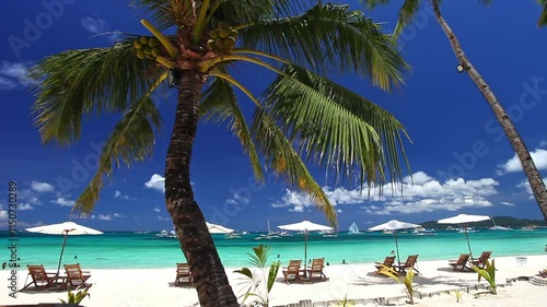 Sun umbrellas and beach chairs on tropical beach with palm trees. Summer vacation. Boracay