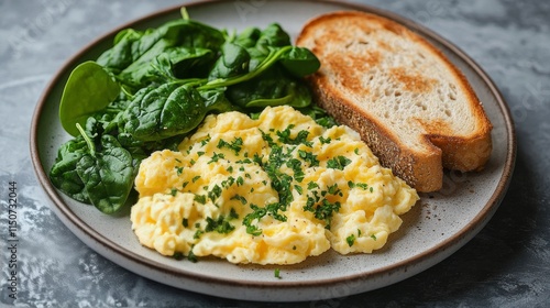 Scrambled eggs with toast and spinach served on a rustic plate for a healthy ...
