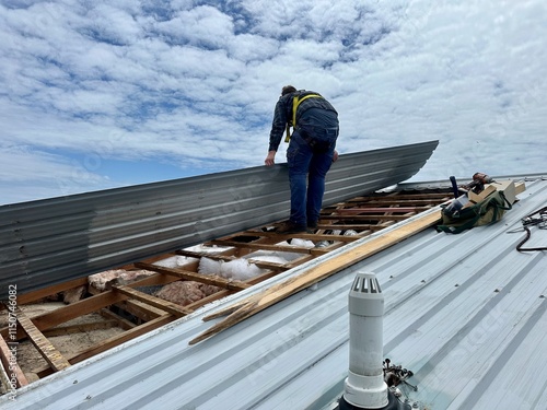 Obraz na płótnie Man wearing a harness standing on the wooden battens of a timber framed roof str