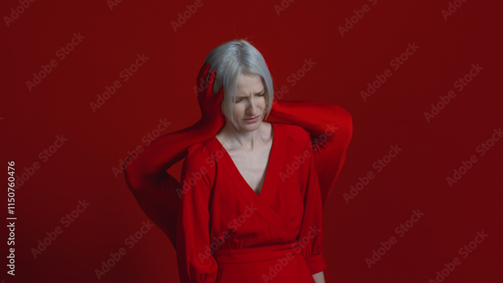Fototapeta premium External and internal condemnation. Public opinion closes my ears to my needs. A feminist concept. Mysterious red hands surround and cover the ears of a woman in red, a photo on a red background.
