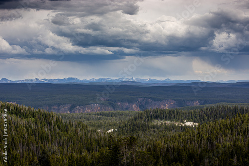 the greater yellowstone valleys during a summer storm with dramatic skies and mountains in the background. grasslands cliffs mountains and storm clouds 