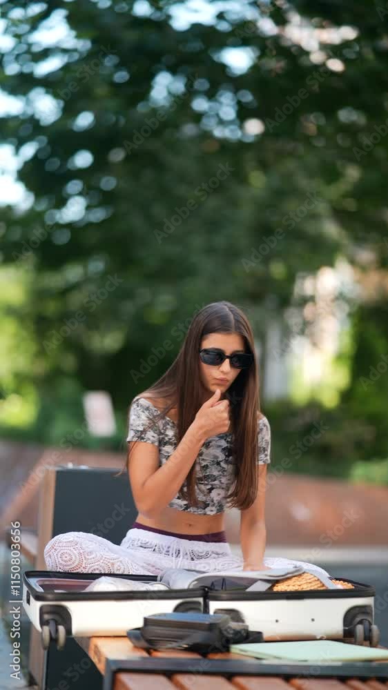 A Stylish Young Woman Wearing Sunglasses and Enjoying Leisure Time Outdoors in the Park A Stylish Young Woman Wearing Sunglasses and Enjoying Leisure Time Outdoors in the Park