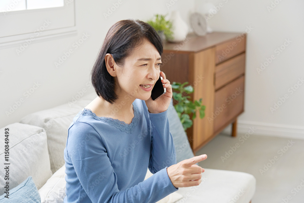 スマホでクレームの電話する中年女性 リビング スマホでクレームの電話する中年女性 リビング