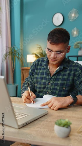 Indian man student freelancer study with notebook write notes making conference video call talking to webcam on laptop computer. Online teacher e-learning in remote chat. Distance education online
