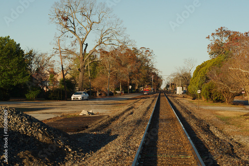 Wide view Railroad Tracks Leading lines  Harlem, GA looking west towards trees on both sides. Early morning sunshine with blue sky.
