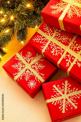 Red Christmas presents with gold snowflake ribbons beneath a lit Christmas tree. Concept of Christmas, gifts, holidays, and festive cheer.