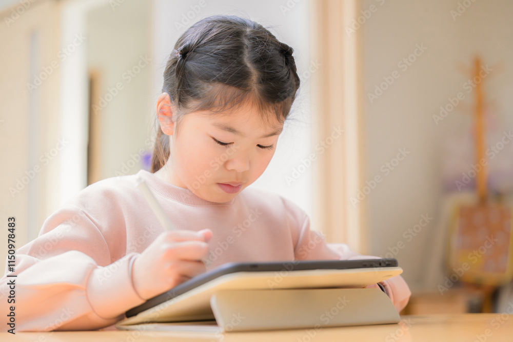 机で座る小学校中学年の笑顔でタブレットで勉強する子供のクローズアップ 机で座る小学校中学年の笑顔でタブレットで勉強する子供のクローズアップ