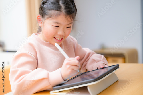 Closeup of a cute smiling kid studying on a tablet with a smiling middle elementary schooler sitting at a desk