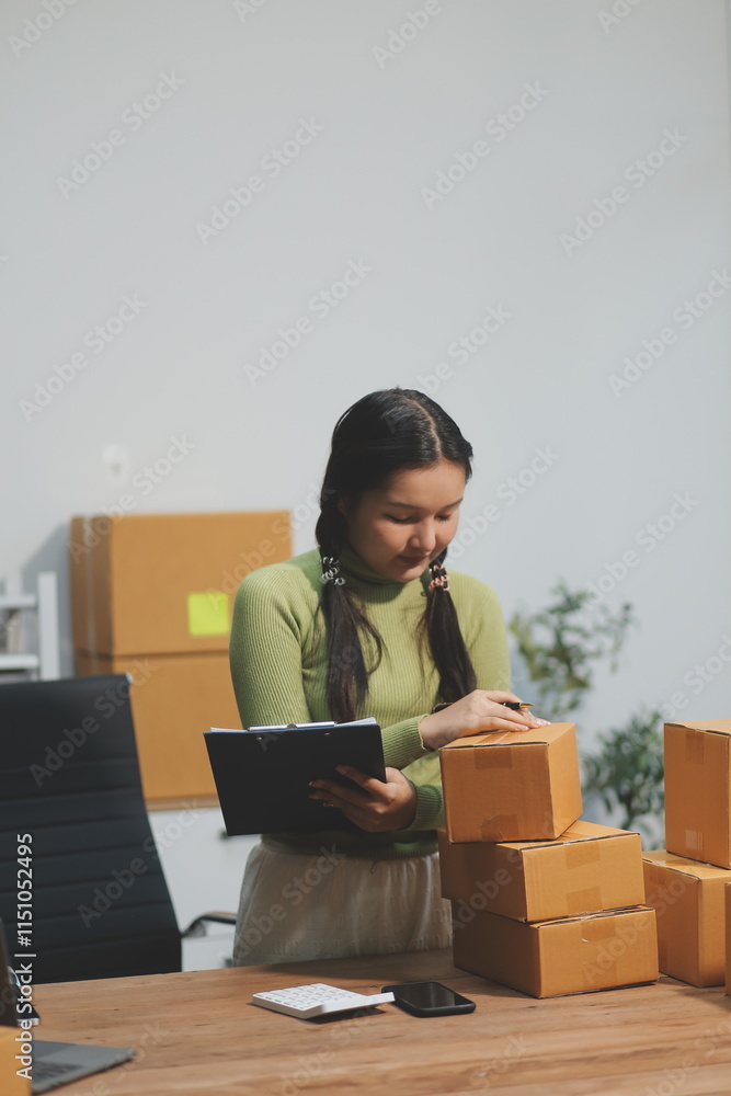 Startup SME small business entrepreneur of freelance Asian woman wearing apron using laptop and box to receive and review orders online to prepare to pack sell to customers, online sme business ideas. Startup SME small business entrepreneur of freelance Asian woman wearing apron using laptop and box to receive and review orders online to prepare to pack sell to customers, online sme business ideas.